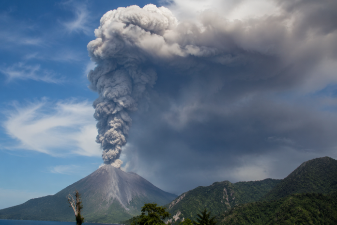 Letusan gunung Dukono dengan kolom abu vulkanik putih kelabu dan hitam menyebar ke arah utara dari puncak gunung di Halmahera